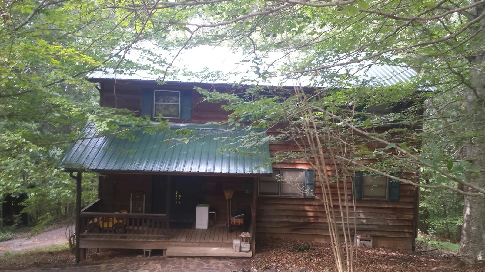 Green metal roof and covered porch on a log cabin in Bayport