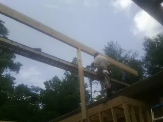 Carpenter setting a ridge beam over a new addition frame — Ice Dam Removal by Roofing Brothers in Bayport